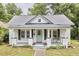 Charming exterior showcasing a well-maintained lawn, metal roof, and a welcoming front porch with gray trim at 2418 Highland Ave, Durham, NC 27704