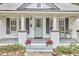 Inviting porch featuring painted brick columns, gray trim, seating, and a charming teal front door at 2418 Highland Ave, Durham, NC 27704