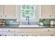 Charming kitchen sink beneath a window with a view of greenery and white cabinets at 2418 Highland Ave, Durham, NC 27704