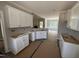 Partially assembled kitchen with white cabinets and view into a living room with a fireplace and lots of natural light at 2744 Rains Mill Rd, Princeton, NC 27569