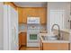 Bright kitchen featuring stainless steel sink, light wood cabinets, and white appliances at 2822 Pickett Rd # 132, Durham, NC 27705