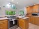 Kitchen featuring stainless steel range, wood cabinets, an island sink, and large windows at 310 Heidinger Dr, Cary, NC 27511