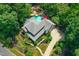 Aerial view of a luxury house with a uniquely shaped pool, red umbrellas, mature trees, and a winding driveway at 4021 Chaumont Dr, Apex, NC 27539