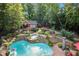Lush backyard oasis featuring a custom pool with waterfalls, hot tub, cabana, and mature landscaping at 4021 Chaumont Dr, Apex, NC 27539