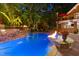 Beautiful pool with a stone water feature, a fire pit, mature landscaping and an outdoor kitchen at 4021 Chaumont Dr, Apex, NC 27539