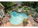 A uniquely shaped pool with waterfalls surrounded by lush landscaping, a cabana, and a custom patio at 4021 Chaumont Dr, Apex, NC 27539