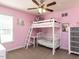 Bright pink bedroom with a bunk bed featuring a ladder and a crib, plus a ceiling fan at 4132 Battle Field Dr, Garner, NC 27529