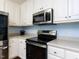 Modern kitchen featuring white cabinets, stainless steel appliances, and an electric stovetop at 4132 Battle Field Dr, Garner, NC 27529