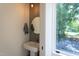 Stylish powder room with a pedestal sink, round mirror, and a view of the outdoors at 414 Chavis Way, Raleigh, NC 27601