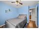 Light blue bedroom featuring a ceiling fan, light gray bed, and an ensuite bathroom entrance at 4221 Ivy Hill Rd, Raleigh, NC 27616