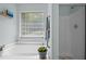 Modern bathroom boasts a luxurious soaking tub, glass block window, and a separate shower at 4508 Alice Dr, Oxford, NC 27565