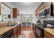 Galley kitchen featuring wood cabinets, laminate counters, wood-look floors, and black appliances at 4508 Alice Dr, Oxford, NC 27565