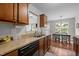 Galley kitchen featuring wood cabinets, laminate counters, wood-look floors, and black dishwasher at 4508 Alice Dr, Oxford, NC 27565