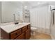 Cozy bathroom with wood cabinets, white countertops, decorative shelves, and a shower with white curtain at 50 Consella Way, Franklinton, NC 27525