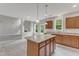 Open-concept kitchen with island, stainless sink, wood cabinets, and an adjacent living area, perfect for entertaining at 5025 Stonewood Pines Dr, Knightdale, NC 27545