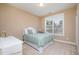 Sunlit bedroom with neutral walls, a bed with a light green cover, and a view of the neighborhood at 522 Finnbar Dr, Cary, NC 27519