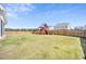 Large fenced backyard with lush green grass and play structure; perfect for families and outdoor entertaining at 604 Salmonberry Dr, Holly Springs, NC 27540