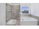 Bathroom featuring a soaking tub under a window and a separate shower with tiled walls and a glass door at 604 Salmonberry Dr, Holly Springs, NC 27540