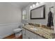 Well-lit bathroom featuring granite countertop, wainscoting, and a framed mirror at 6717 Ebon Ct, Raleigh, NC 27615