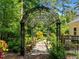 Arched metal garden feature surrounded by mature trees and plantings creates a magical backyard retreat at 676 Whitehurst, Pittsboro, NC 27312