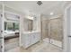 Bright bathroom with a glass enclosed shower, neutral tile and white vanity with double sinks at 707 Newlyn Dr, Raleigh, NC 27606