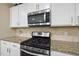 Modern kitchen with stainless steel gas range, microwave, granite counters, and white cabinets at 707 Newlyn Dr, Raleigh, NC 27606