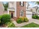 Charming home featuring a brick facade, white siding, and an attached two-car garage with green bushes in front at 8013 Morrell Ln, Durham, NC 27713