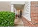 Inviting covered front porch with brick accents and elegant columns, leading to a black front door at 8013 Morrell Ln, Durham, NC 27713