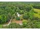 Aerial view of the property, showing the home nestled in a wooded area and open yard space at 8089 Crawford Currin Rd, Oxford, NC 27565