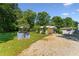 View of the backyard featuring multiple sheds, gravel driveway, and mature trees at 8089 Crawford Currin Rd, Oxford, NC 27565