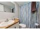 Bathroom with a single sink vanity, toilet, and a shower with a blue striped curtain at 8089 Crawford Currin Rd, Oxford, NC 27565
