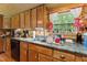 Close-up of the rustic kitchen featuring wooden cabinets, dark countertops, and a window at 8089 Crawford Currin Rd, Oxford, NC 27565