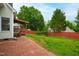 A well-maintained backyard with a brick patio, a wooden fence, lush green grass, and mature trees, creating a serene outdoor space at 102 W Hill Dr, Cary, NC 27519