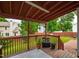 View of the covered deck with a wooden railing, wooden flooring, and potted plants overlooking a grassy yard and neighboring houses at 102 W Hill Dr, Cary, NC 27519