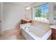 Bright bathroom with large tub, tile surround, and window at 1021 Benay Rd, Morrisville, NC 27560