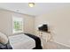 Cozy bedroom with neutral walls, a window view, and a television on a small table at 105 Putters Ct, Durham, NC 27703