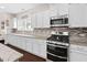 White cabinets complement a granite countertop, stainless steel appliances and modern mosaic backsplash in a bright kitchen at 105 Putters Ct, Durham, NC 27703