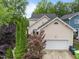 Exterior angle showcases the garage, deck, and landscaping of the house, with mature trees at 10579 Evergreen Spring Pl, Raleigh, NC 27614
