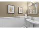 Updated powder room with white wainscoting, tan colored walls and modern art pieces at 10579 Evergreen Spring Pl, Raleigh, NC 27614