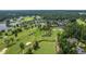 Aerial view of the expansive golf course, lake, tennis court, and clubhouse surrounded by lush greenery at 108 Vescova Ln, Morrisville, NC 27560