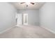 Neutral bedroom with a ceiling fan and neutral carpeting with an open doorway to a stairwell at 112 River Dell Townes Ave, Clayton, NC 27527