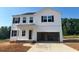 A bright white two-story home featuring black shutters and a spacious two-car garage under a clear blue sky at 120 Cordoba Dr, Franklinton, NC 27525