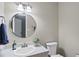 Bright bathroom featuring a round mirror over the sink and a toilet, complemented by decorative flowers at 1200 Collington Dr, Cary, NC 27511