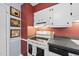 Galley kitchen equipped with white appliances, stylish white cabinets and grey counters, complemented by decorative wall art at 1200 Collington Dr, Cary, NC 27511