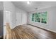 Bright bedroom with wood-look floors, a window view, and access to dual closets and hallway at 1216 Briarwood Dr, Mebane, NC 27302