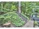 Landscaped backyard with stone stairs, lush greenery, and a quaint shed, creating a serene outdoor space at 126 Weaver Rd, Chapel Hill, NC 27514
