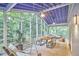 Spacious screened porch with a blue ceiling, ceiling fans, wooden furniture, and a tranquil view of the surrounding woods at 126 Weaver Rd, Chapel Hill, NC 27514