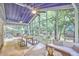 Expansive screened porch with a blue ceiling, comfortable seating, dining space, and serene views of the lush greenery at 126 Weaver Rd, Chapel Hill, NC 27514
