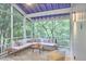 Relaxing screened porch featuring a blue ceiling, white trim, sectional sofa, and a peaceful view of the wooded surroundings at 126 Weaver Rd, Chapel Hill, NC 27514