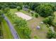 An aerial view of the property featuring a sandy arena, outbuildings, and surrounding landscaping at 12823 Summerwind Trl, Rougemont, NC 27572